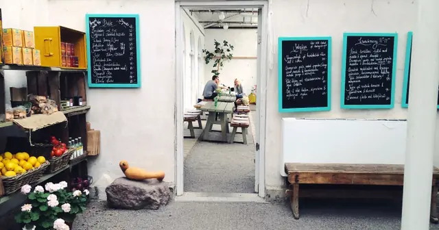Cafeteria com cardápios escritos a giz nas paredes e clientes à mesa, capa do guia de cardápio digital com pedido pelo WhatsApp