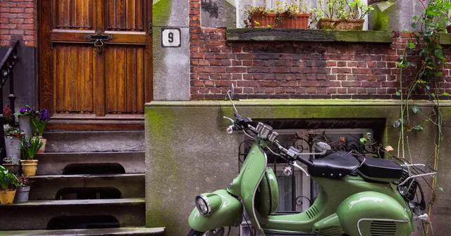 Lambreta verde estacionada diante de uma parede de tijolos, capa do guia de relatórios de vendas do delivery