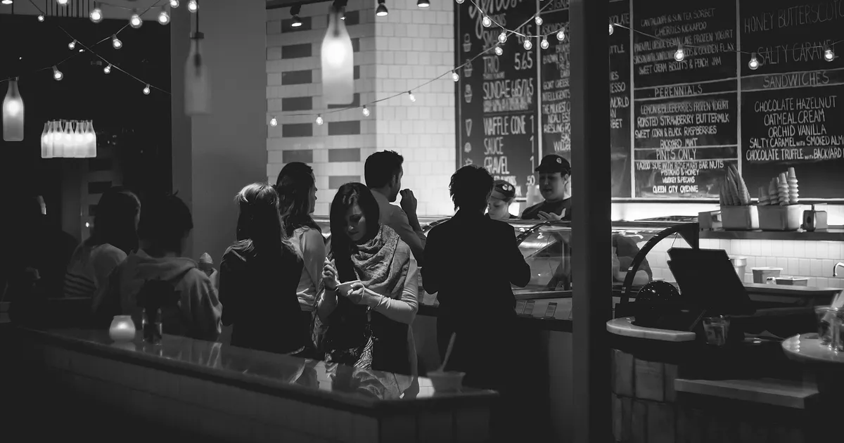 Fila de clientes em frente ao balcão de um café, capa do guia de retenção de clientes no delivery