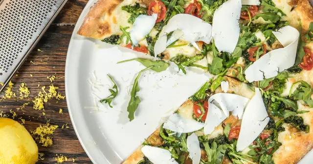 Pizza vista de cima com rúcula, tomate-cereja e lascas de queijo, capa do guia para vender mais no delivery sem comissão